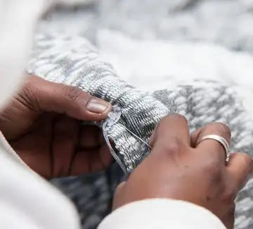 Gray and white knitted sweater cuff with a ribbed texture.
